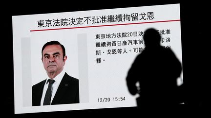 Un écran diffuse les dernières informations qui concernent&nbsp;Carlos Ghosn, PDG de Renault, dans une rue de Tokyo (Japon). (BEHROUZ MEHRI / AFP)