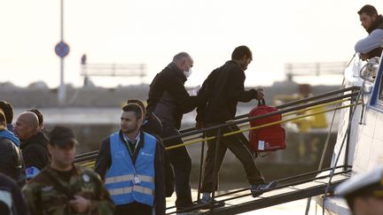 Un agent de Frontex raccompagne un migrant sur un bâteau turc, le 4 avril 2016 sur l'île grecque de Lesbos. (REUTERS/Giorgos Moutafis)