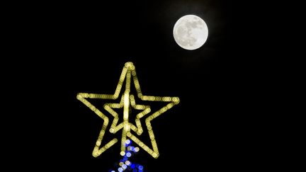 La "super Lune" au-dessus d'un arbre de Noël, à Sofia, la capitale bulgare, le 1er janvier 2018. (DIMITAR DILKOFF / AFP)