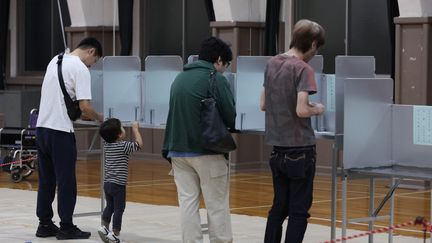 Des Japonais déposent leur bulletin lors des élections générales dans un bureau de vote de Tokyo, le 27 octobre 2024. (TETSUJI NOGUCHI / YOMIURI / AFP)