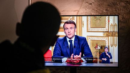 Une personne regarde l'allocution d'Emmanuel Macron à la télévision, le 5 décembre 2024. (MARTIN ROCHE / MAXPPP)