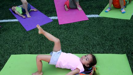 Il n'y a pas d'âge pour commencer ! En témoigne cette petite fille qui s'essaie au yoga dans le parc botanique Babirkoy à Istanbul, le 21 juin. (BERK OZKAN / ANADOLU AGENCY / AFP)