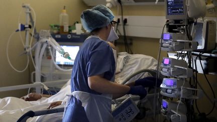 Une infirmière au chevet d'un malade du Covid-19&nbsp;au sein de&nbsp;l'unité de soins intensifs de l'hôpital privé des Peupliers, à Paris, le 7 avril 2020. (THOMAS COEX / AFP)