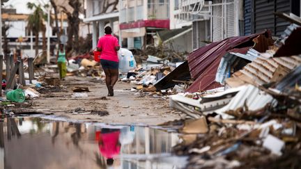 Une&nbsp;habitante de Saint-Martin porte de l'eau dans une rue de Marigot, le 12 septembre 2017, après le passage de l'ouragan Irma sur l'île. (MARTIN BUREAU / AFP)