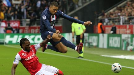 L'attaquant du PSG Kylian Mbappé saute au-dessus du défenseur de Reims&nbsp;Andreaw Gravillon, lors du match&nbsp;de la 10e journée de Ligue 1 entre Reims et Paris le 8 octobre 2022. (FRANCOIS NASCIMBENI / AFP)