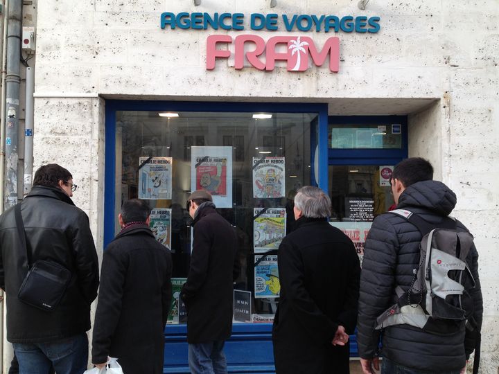 Des groupes s'arr&ecirc;tent devant la vitrine de cette agence de voyages, d&eacute;cor&eacute;e avec de vieilles unes de&nbsp;Charlie Hebdo.&nbsp; (JULIE RASPLUS / FRANCETV INFO)