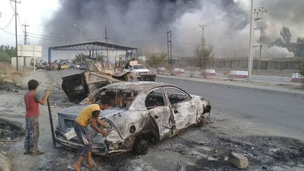 Des enfants assistent &agrave; des affrontements entre les forces de s&eacute;curit&eacute; irakiennes et des jihadistes&nbsp;du groupe l'Etat islamique en Irak et au Levant &agrave; Mossoul (Irak), le 10 juin 2014. (REUTERS)