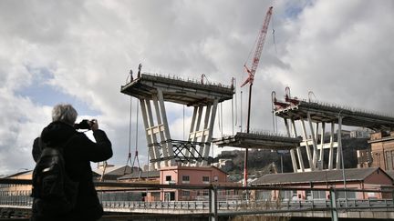 Une personne prend une photo du démarrage du démontage du pont Morandi, à Gênes, en Italie. (MARCO BERTORELLO / AFP)