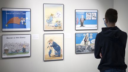 Une personne regarde des caricatures représentant Donald Trump lors de la dernière préparation avant la nouvelle exposition "Ça se dessine pour la Maison Blanche" à la Maison du dessin de presse, à Morges, en Suisse, le 24 octobre 2020. (LAURENT GILLIERON / EPA/ NEWSCOM / MAXPPP)