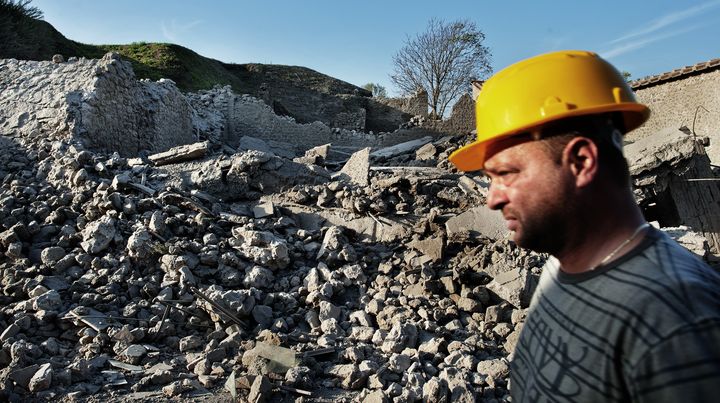 Un ouvrier passe devant les ruines de la Maison des gladiateurs, qui s'est effondr&eacute;e le 6 novembre 2010, sur le site arch&eacute;ologique de Pomp&eacute;i (Italie). (ROBERTO SALOMONE / AFP)