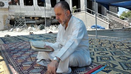 Un Palestinien lit le Coran dans la cour d'une mosqu&eacute;e d&eacute;truite, vendredi 1er ao&ucirc;t 2014.&nbsp; (MOHAMMED TALATANE / ANADOLU AGENCY)