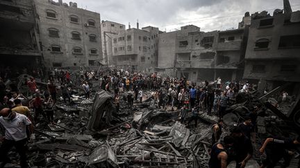 Des habitants de la bande de Gaza dans les décombres, le 27 octobre 2023. (ALI JADALLAH / ANADOLU / AFP)