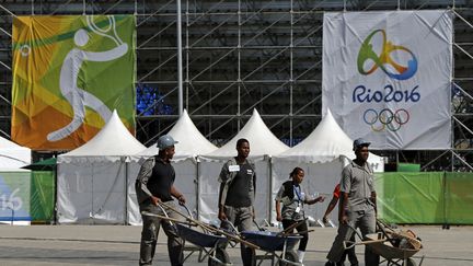 Des ouvriers transportent des outils à l'extérieur du stade de tennis à Rio (Brésil), le 1er août 2016. (SERGIO MORAES / REUTERS)