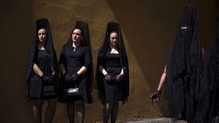 Pour assister aux processions, les femmes rev&ecirc;tent la traditionnelle mantille, une &eacute;charpe de dentelle dont elles se couvrent la t&ecirc;te tandis que les hommes endossent un costume noir. (EMILIO MORENATTI / AP / SIPA)