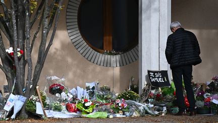 Un homme se recueille devant le collège du Bois d'Aulne à Conflans-Sainte-Honorine (Yvelines), en hommage à Samuel Paty, professeur assassiné, le 19 octobre 2020.&nbsp; (ANNE-CHRISTINE POUJOULAT / AFP)