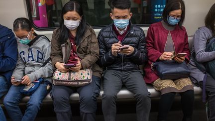 Des personnes portent des masques dans un train à Hong Kong, le 25 janvier 2020. (DALE DE LA REY / AFP)