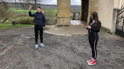 A Piblange, il faut aller sur la place de l'église pour tenter de capter un bout de réseau. Ici, Nicolas et Maëlle essaient tant bien que mal de faire fonctionner leur portable.&nbsp; (ALIENOR VINCOTTE / FRANCEINFO)