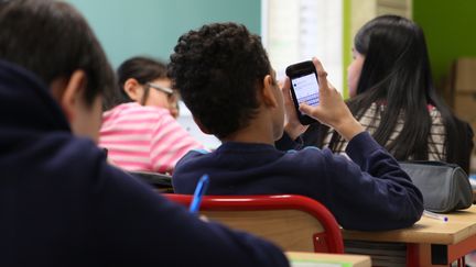 Un &eacute;l&egrave;ve de CM2 r&eacute;dige un ha&iuml;ku sur un smartphone, &agrave; l'&eacute;cole &eacute;l&eacute;mentaire B de l'avenue d'Ivry, &agrave; Paris, le 9 avril 2015. (CAMILLE CALDINI / FRANCETV INFO)