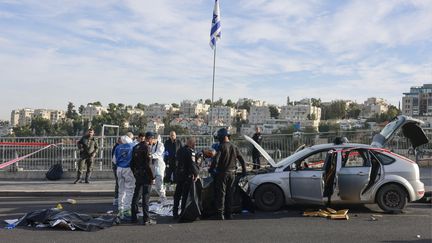 Les forces de sécurité israéliennes devant le véhicule des assaillants, le 30 novembre 2023, après une attaque commise à l'arme à feu à Jérusalem. (MENAHEM KAHANA / AFP)