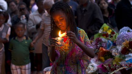 Une fillette allume une bougie &nbsp;pour l'ancien pr&eacute;sident Nelson Mandela, &agrave; Johannesbourg, le 8 d&eacute;cembre 2013. (PEDRO UGARTE / AFP)