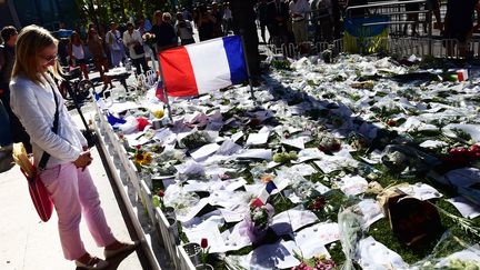 Une femme se recueille devant le mémorial aux victimes de l'attentat de la promenade des Anglais, à Nice, le 16 juillet 2016. (GIUSEPPE CACACE / AFP)