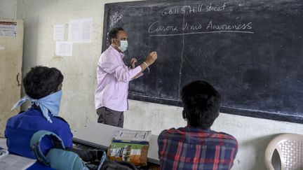 Un enseignant et deux de ses élèves dans un lycée de Secunderabad le 4 mars 2020 (NOAH SEELAM / AFP)