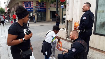 Les policiers&nbsp;distribuent des bonbons dans les rues de Saint-Denis (NATHALIE REVENU / MAXPPP)