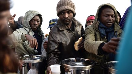 Des migrants et réfugiés font la queue, mardi 9 mai, pour recevoir café chaud et nourriture avant d'être évacués des campements illicites où ils vivent depuis plusieurs semaines porte de la Chapelle, dans le nord de Paris. (PHILIPPE LOPEZ / AFP)