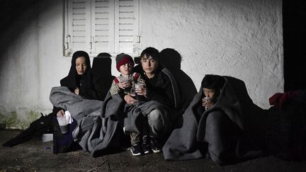 Un nouveau groupe de réfugiés, dont 19 enfants, sont arrivés ce vendredi et patientent contre une maison sur l'île grecque de Lesbos. (LOUISA GOULIAMAKI / AFP)