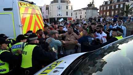 Des manifestants d'extrême droite face à la police, le 4 août 2024, à Weymouth, au Royaume-Uni. (JUSTIN TALLIS / AFP)