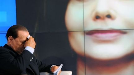 Silvio Berlusconi avec le portrait de sa femme en arrière-plan pendant l'enregistrement d'une émission de la RAI (© AFP PHOTO / TIZIANA FABI)