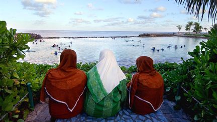 Trois femmes face à&nbsp;la plage artificielle de Malé aux Maldives. (EMMANUEL DUNAND / AFP)