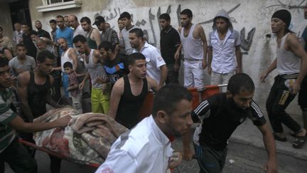 Des secouristes transportent un corps extrait des d&eacute;combres d'un immeuble d&eacute;truit par un bombardement isra&eacute;lien, le 25 juillet 2014s &agrave; Rafah, dans la bande de Gaza. (SAID KHATIB / AFP)