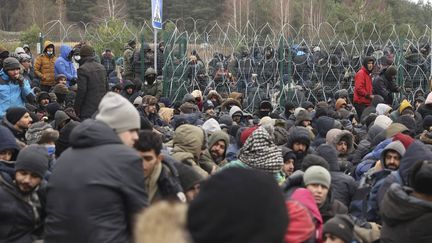 Des migrants se rassemblent devant une clôture de barbelés au poste de contrôle Kuznitsa à la frontière entre la Biélorussie et la Pologne, le 15 novembre 2021. (OKSANA MANCHUK / AP / SIPA)