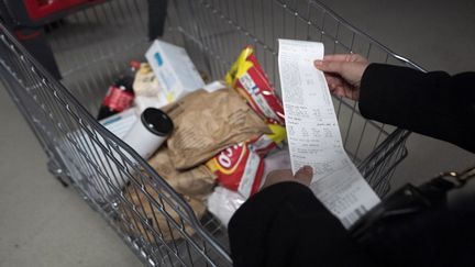 Une consommatrice consulte son ticket de caisse à Paris, le 4 mars 2023. (SERGE TENANI / HANS LUCAS / AFP)