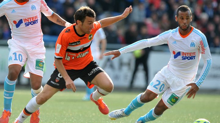 L'attaquant de l'OM Andre Ayew se d&eacute;fait du marquage du lorientais Yann Jouffre, lors du match entre les deux &eacute;quipes le 27 avril 2013. (FRANK PERRY / AFP)