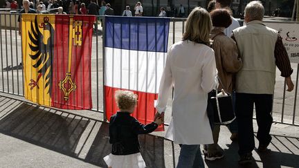 Des &eacute;lecteurs passent devant un drapeau fran&ccedil;ais et un drapeau de la ville de Gen&egrave;ve pour se rendre dans un bureau de vote &agrave; l'occasion du premier tour de l'&eacute;lection pr&eacute;sidentielle fran&ccedil;aise, le 22 avril 2007 &agrave; Gen&egrave;ve (Suisse). (FABRICE COFFRINI / AFP)