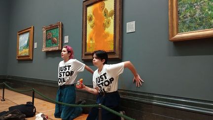 Deux militantes écologistes de "Just stop oil" lors de leur action contre la toile "Les tournesols" de Vincent Van Gogh, à la National Gallery de Londres (Royaume-Uni), le 14 octobre 2022. (HANDOUT / JUST STOP OIL)