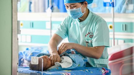 Une infirmière et un nouveau-né à Anlong, dans la province de Guizhou (Chine), le 11 mai 2020 (STR / AFP)