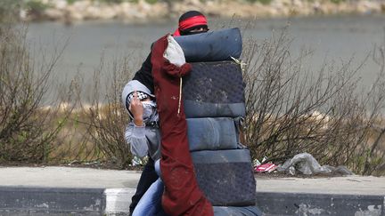 Des Palestiniens se prot&egrave;gent avec un si&egrave;ge de voiture lors d'affrontements avec des militaires isra&eacute;liens &agrave; Ramallah (Palestine), le 19 f&eacute;vrier 2013. (DARREN WHITESIDE / REUTERS)