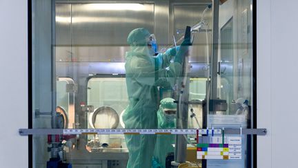 Un opérateur travaille devant un isolateur pour remplir des seringues dans une zone stérile, chez Sanofi à Val-de-Reuil (Eure), le 10 juillet 2020. (JOEL SAGET / AFP)