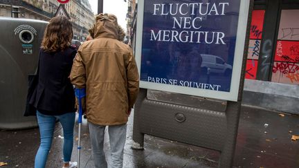 "Paris se souvient", le 13 novembre 2016.&nbsp;Une victime des attentats passe devant l'affiche qui porte la devise de Paris : 'Fluctuat Nec Mergitur' 'Il&nbsp;est battu par les flots mais ne sombre pas'. (Illustration) (ROBERT DEYRAIL / GAMMA-RAPHO / GETTY IMAGES)