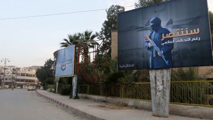 Une affiche de Daech dans les rues de la ville de Raqqa (est de la Syrie) qu'il contrôle, sur laquelle on peut lire : «Nous gagnerons malgré la coalition internationale» (29 octobre 2014). (Nour FOURAT / REUTERS)