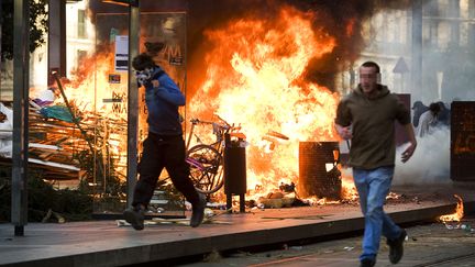 Des manifestants courent devant des bouteilles de p&eacute;trole explosant sur des v&eacute;los et des poubelles, &agrave; Nantes, apr&egrave;s une manifestation contre un projet d'a&eacute;roport, le 24 mars 2012. (JEAN-SEBASTIEN EVRARD / AFP)