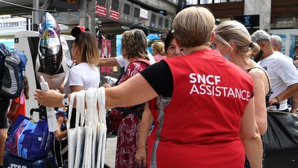 Un agent de la SNCF renseigne des voyageurs, à la Gare de Lyon, à Paris, en juillet 2022. (BERTRAND GUAY / AFP)