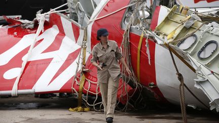 Un enqu&ecirc;teur d'Airbus marche,&nbsp;le 12 janvier 2015, &agrave; c&ocirc;t&eacute; d'un morceau de l'avion d'AirAsia&nbsp;&eacute;chou&eacute; en mer. (DARREN WHITESIDE / REUTERS)