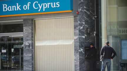 Des Chypriotes retirent de l'argent &agrave; un distributeur de la&nbsp;Bank of Cyprus ferm&eacute;e, le 23 mars 2013 &agrave; Nicosie (Chypre). (VLADIMIR ASTAPKOVICH / RIA NOVOSTI / AFP)