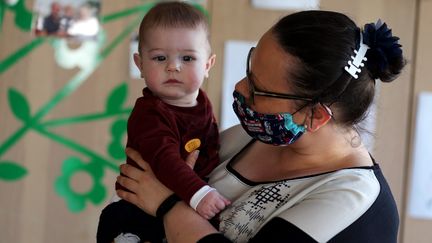 Une professionnelle tient un jeune enfant dans une micro-crèche à Carvin (Pas-de-Calais), le 21 avril 2020. (LUDOVIC MAILLARD / MAXPPP)