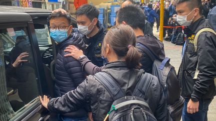 Le rédacteur en chef de la publication Stand News, Patrick Lam, est conduit menotté dans un véhicule par les policiers, le 29 décembre 2021 à Hong Kong. (EYEPRESS NEWS / AFP)