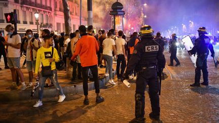 Des CRS encadrent des supporters qui célèbrent la qualification du PSG en finale de la Ligue des champions, le 18 août 2020 (JULIEN MATTIA / ANADOLU AGENCY)